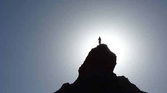 Photo of man atop mountain, without peer, all alone.